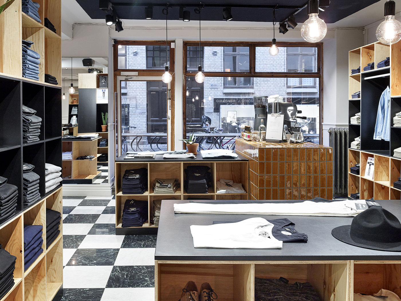 Butikskoncept för varumärket Dr. Denim. Inredning i ljus och målad plywood med schakmönstrat stengolv, Nakna glödlampor hängades i tak